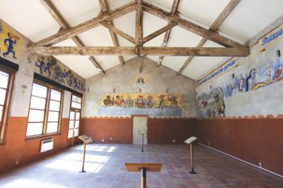 Salle mansardée, comportant des dessins au mur se rapprochant de scènes religieuses caricaturées telles que les 12 apôtres - Agrandir l'image 3 sur 6, fenêtre modale