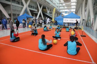 des enfants assis de par et d'autre un petit terrain de volleyball monté en intérieur avec un petit filet. ils sont assis deux par deux face à face et se renvoient des ballons - Agrandir l'image 9 sur 15, fenêtre modale