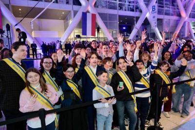Groupe d’enfants et adolescents portant des écharpes officielles, rassemblés et saluant le public dans un hall événementiel - Agrandir l'image 14 sur 20, fenêtre modale