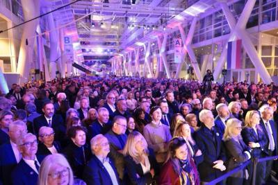 Grande foule rassemblée dans un hall éclairé en violet et bleu pour un événement officiel - Agrandir l'image 5 sur 20, fenêtre modale