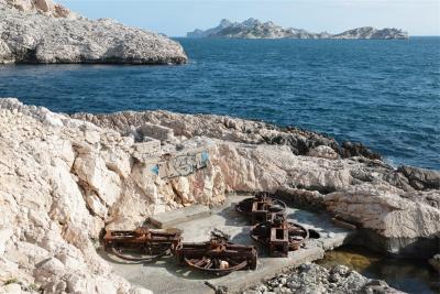 Vue des rochers en bord de mer. On devine les restes rouillés de l'installation du téléscaphe : 4 roues qui permettaient d'actionner les câbles. - Agrandir l'image 1 sur 5, fenêtre modale
