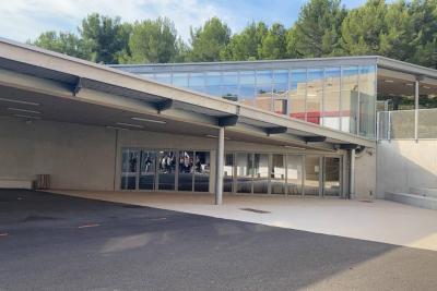 Vue extérieure d’un bâtiment moderne avec de grandes baies vitrées et un auvent couvrant l’entrée. Des arbres sont visibles en arrière-plan. - Agrandir l'image 1 sur 6, fenêtre modale