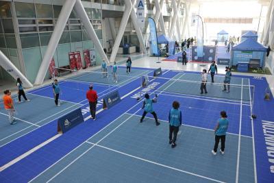 Participants jouant au badminton sur des terrains bleus à l’intérieur d’un hall. - Agrandir l'image 6 sur 15, fenêtre modale