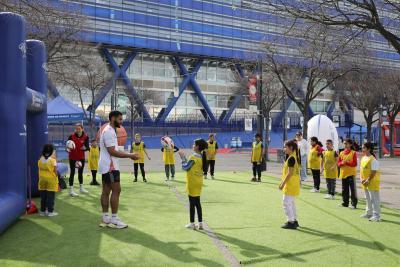 Atelier rugby en plein air avec des enfants en gilet jaune et un éducateur. - Agrandir l'image 2 sur 15, fenêtre modale